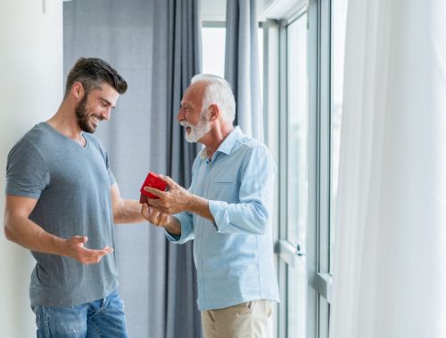 Hombre mayor dando un regalo a un hombre mas joven